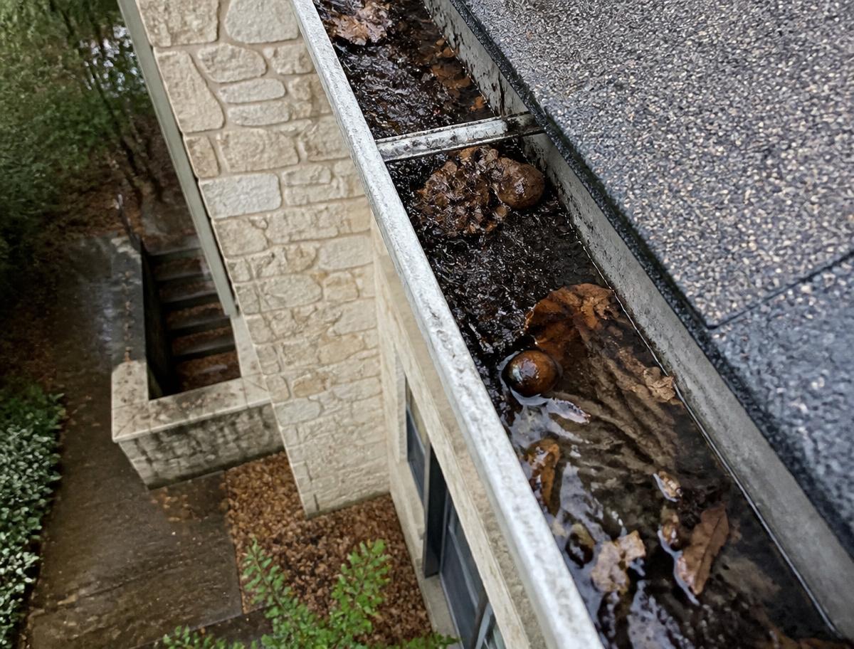 Aluminum gutter packed with wet leaves and debris on an Austin home before cleaning